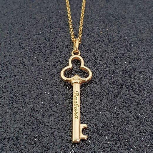 gold key necklace on black close